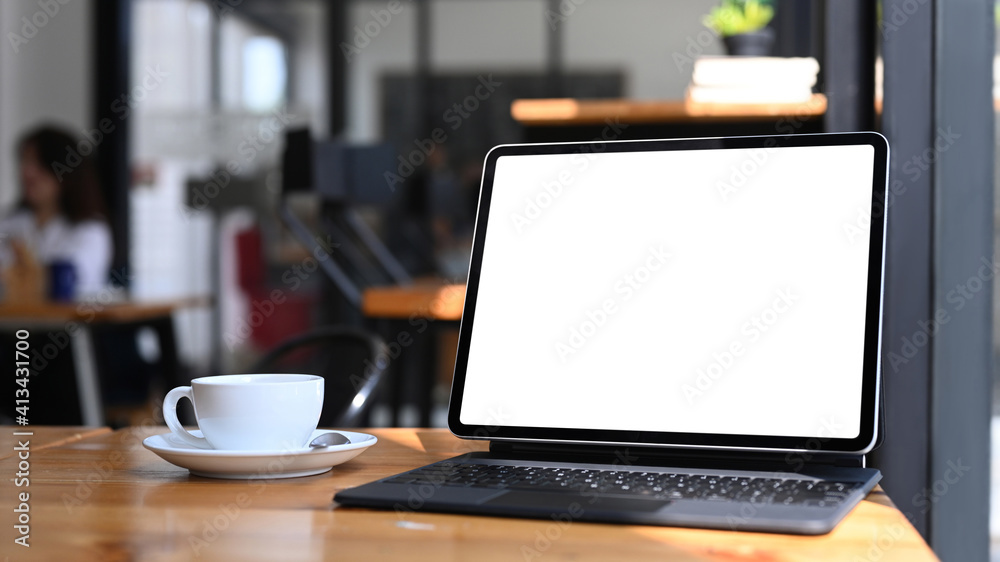 Close up view of computer tablet with empty screen and coffee cup on wooden table. Close up view of computer tablet with empty screen and coffee cup on wooden table.
