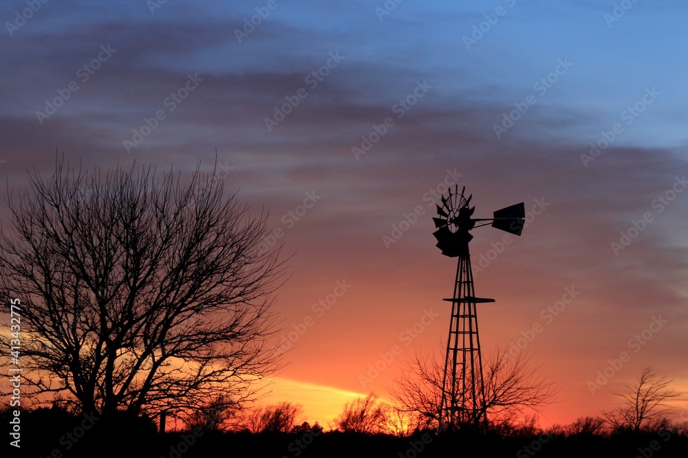 Fototapeta premium Kansas colorful Sunset with clouds and a Windmill silhouette out in the country north of Hutchinson Kansas USA.