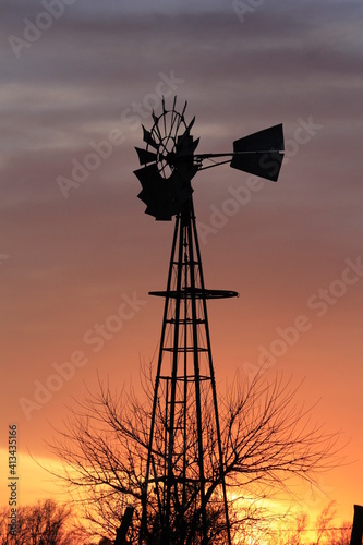 Kansas colorful Sunset with clouds and a Windmill silhouette out in the country north of Hutchinson Kansas USA.