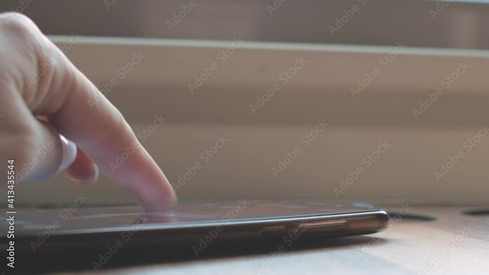 Passenger being near the window in a moving vehicle, with the fingers of a brush with white manicure on the nails, leafs through the screen of a smartphone. Close-up. Passenger being near the window in a moving vehicle, with the fingers of a brush with white manicure on the nails, leafs through the screen of a smartphone. Close-up.