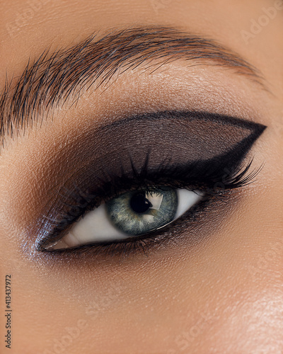 Beautiful macro shot of female eye make-up in smoky eyes style. Blue eye. Creative make-up. Perfect shape make-up and long lashes. Cosmetics. Beautiful eyes make-up. Close-up