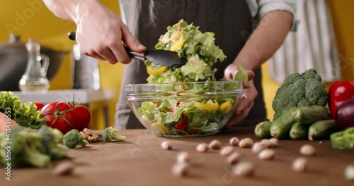 Chef mixing healthy green salad in a bowl. Cooker cooking healthy vegetarian meal, 4k footage