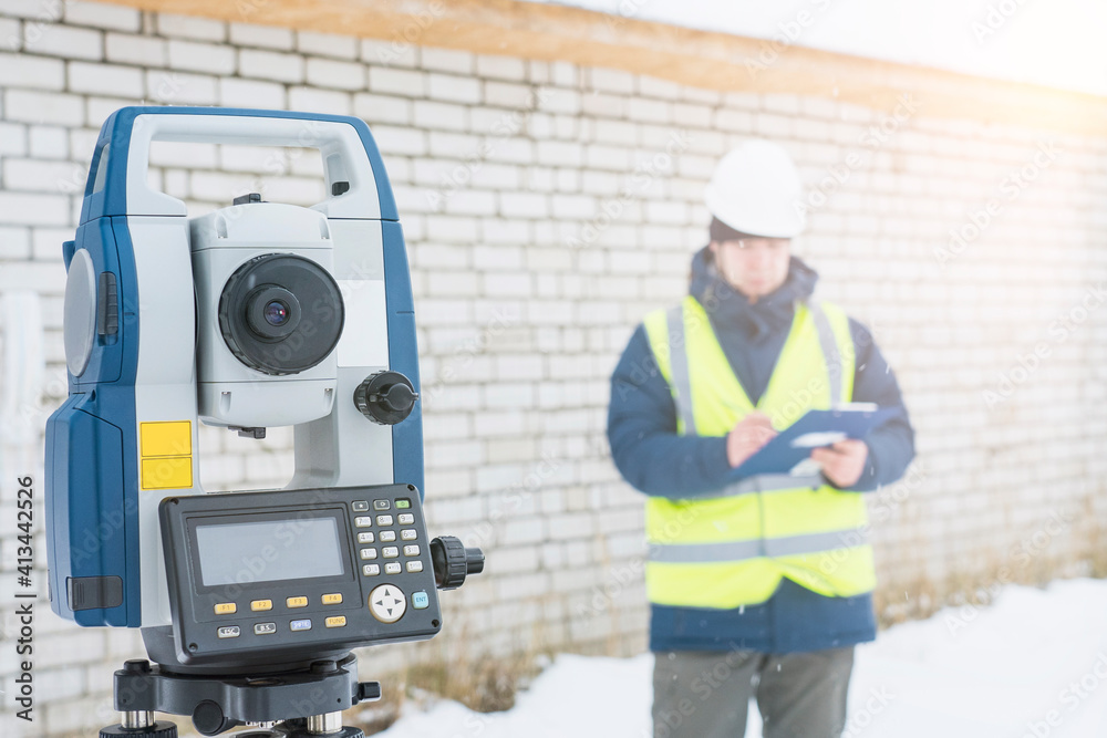 engineer surveyor works with an electronic total station, a tool for performing geodetic, construction and cadastral works on the ground, selective focusing, tinting. engineer surveyor works with an electronic total station, a tool for performing geodetic, construction and cadastral works on the ground, selective focusing, tinting.