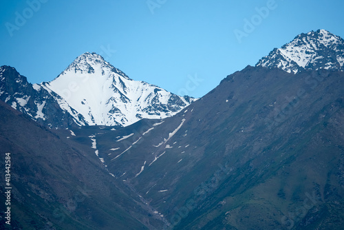 The nature of Kyrgyzstan. Summer. Mountain landscape. Among green valleys, mountains are visible at middle of the day. Tien Shan Mountains, Kyrgyzstan.