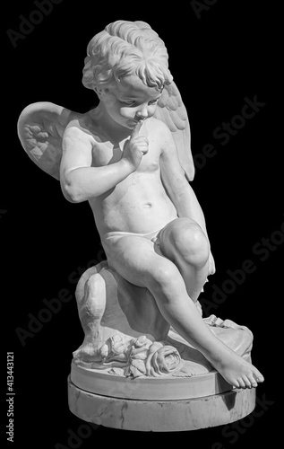 White angel figurine isolated on black background. Cupid sculpture. Stone statue of young cherub