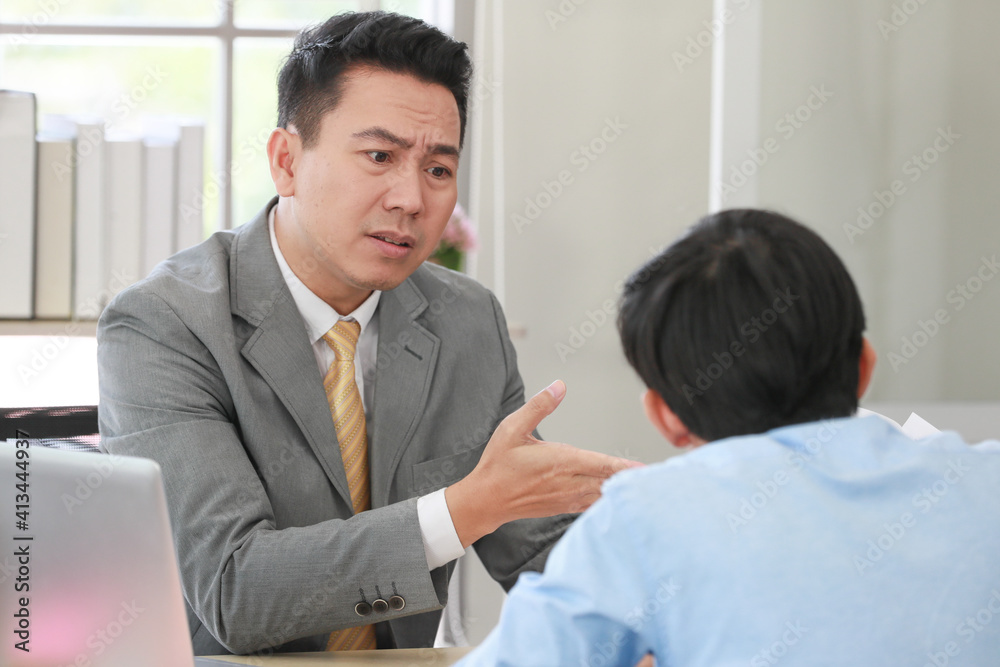 Executive boss Asian businessman in suit holding paperwork and blaming young employee with anger and serious gesture look like he comments as disagree or unacceptable for his project work