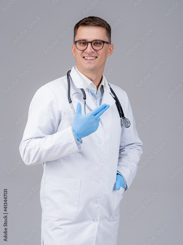 Doctor with stethoscope and latex glasses on hands poses to the camera. Medic in glasses on gray background. Closeup. Doctor with stethoscope and latex glasses on hands poses to the camera. Medic in glasses on gray background. Closeup.