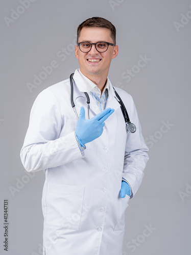 Doctor with stethoscope and latex glasses on hands poses to the camera. Medic in glasses on gray background. Closeup.
