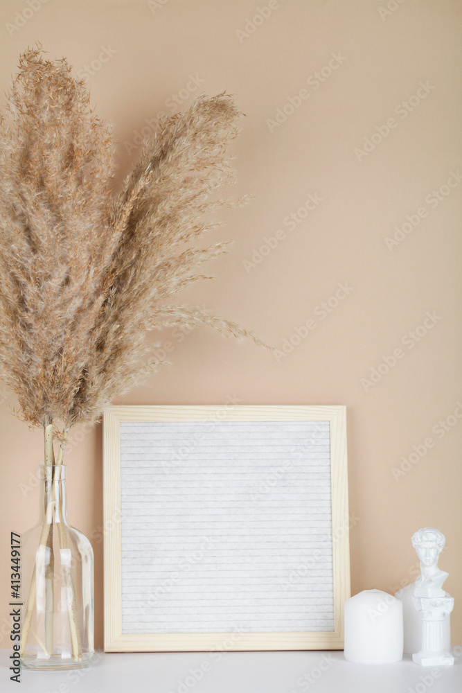 Dried pampas grass in vases, candles and felt letter board on beige background, interior, home design. Art concept. copy space