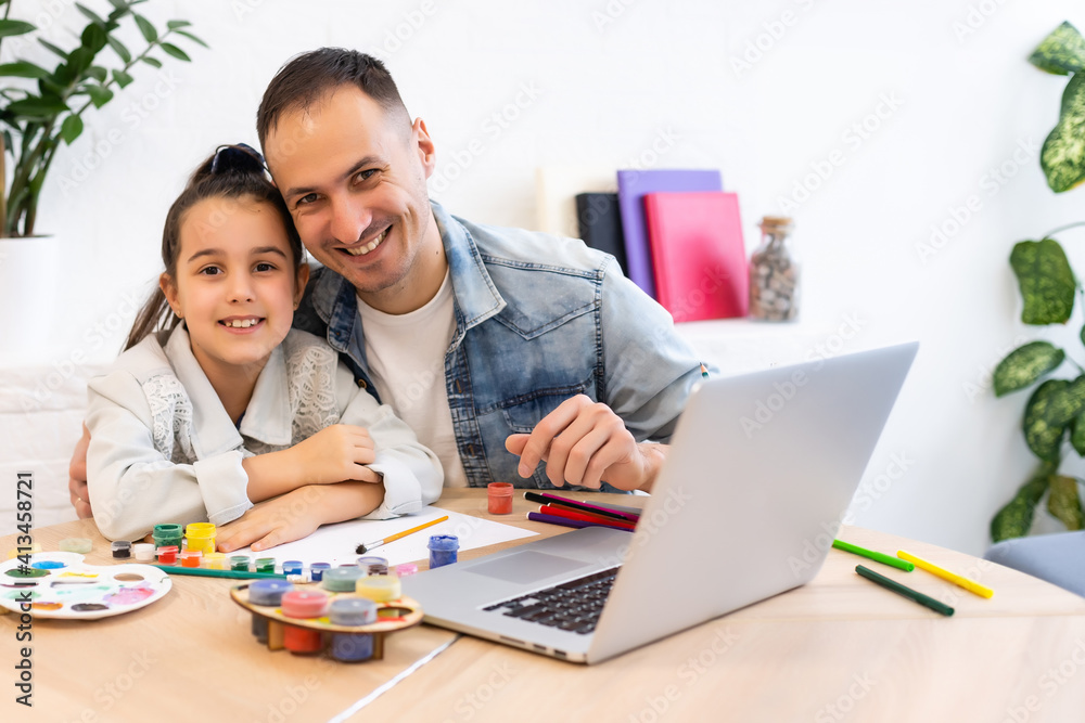 Young father helping her daughter with her school project on laptop at home Young father helping her daughter with her school project on laptop at home
