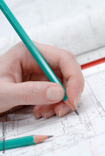 Woman's hand holding pencil and architectural plans