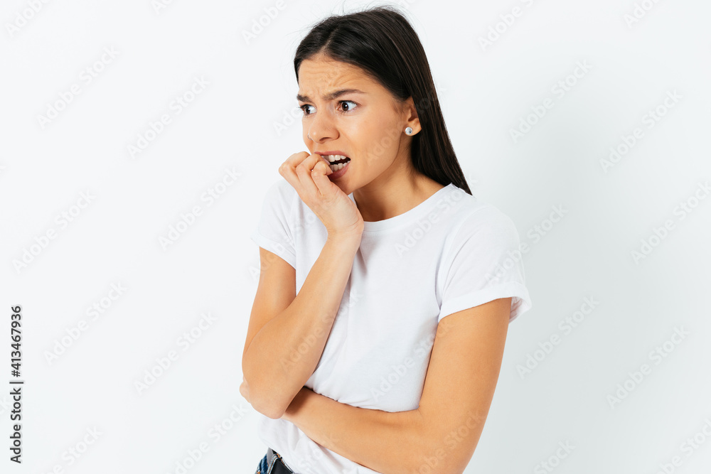 Scared anxious young woman biting nails looking to the side Scared anxious young woman biting nails looking to the side