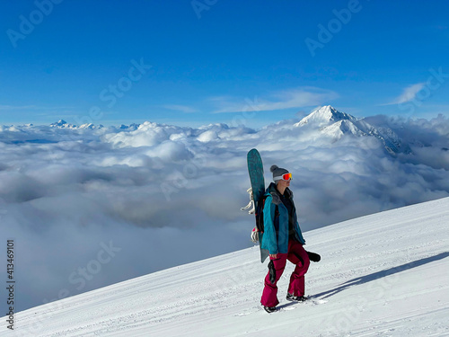 Young woman snowboarding in closed Krvavec ski resort hikes up a groomed slope. photo