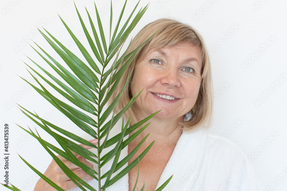 Naklejka premium Senior woman smiling Anti-aging concept with palm leaf. Mature woma face after spa treatment. Old age in joy, plastic surgery clinic, cutie grandmother, cosmetology, new senior