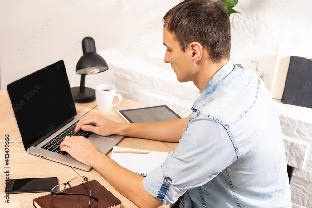 Portrait of a man working at home on some project, he is sitting at a table, drawing ideas on a notebook, with his laptop in front of him. Portrait of a man working at home on some project, he is sitting at a table, drawing ideas on a notebook, with his laptop in front of him.