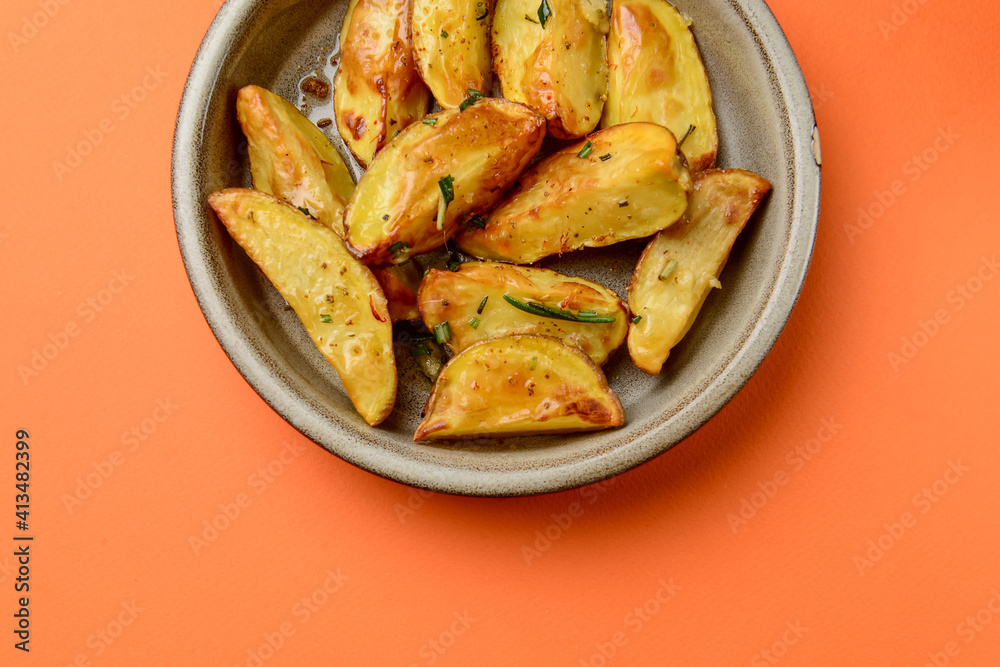 Baked potato with rosemary served in a ceramic bowl over orange background. Delicious idea for dinner. Baked potato with rosemary served in a ceramic bowl over orange background. Delicious idea for dinner.