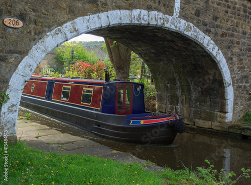 A leisurely boat emerges under the bridge of the Leeds and Liverpool canal at Dowley Gap near Bingley in West Yorkshire photo