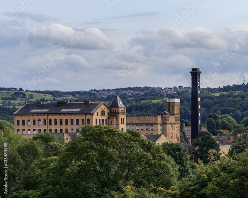 The Victorian textile mill and chimney provide a stark contrast against the green background provided by the countryside around Bingley in West Yorkshire photo