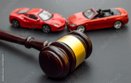 Fotografija Judge gavel with red toy cars on black.