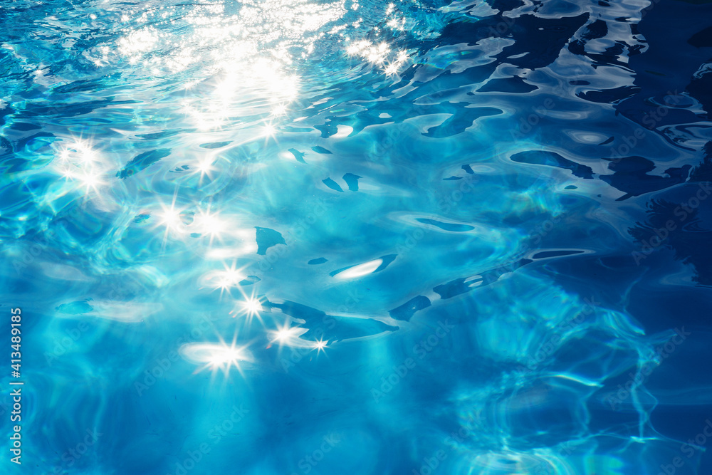 Obraz premium Background of the sun reflections in the surface of the blue water of a pool during summer