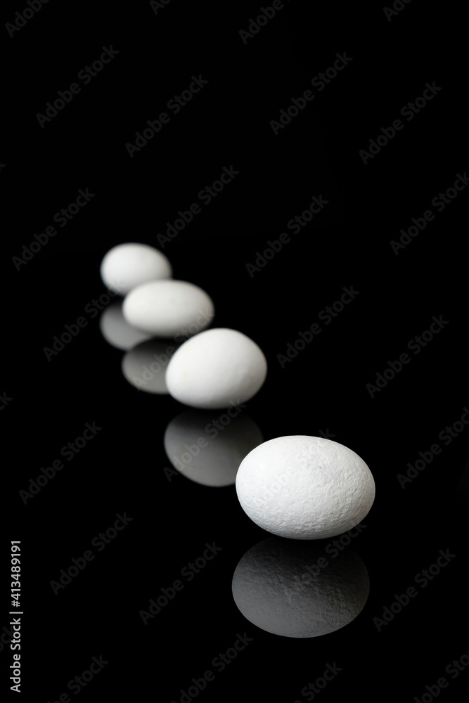 White sea pebbles on black background with mirror reflection. White sea pebbles on black background with mirror reflection.