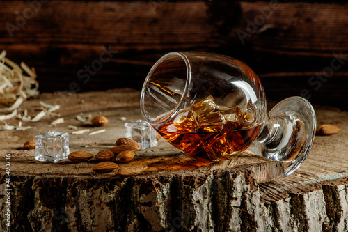 Whiskey with ice or brandy or rum in glass on rustic background. Whiskey with ice in a glass. Whiskey or brandy. Selective focus. Rum with ice on wooden background.