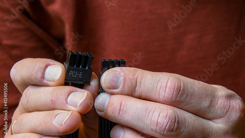 Male fingers with damaged skin injuries and nails without manicure. Closeup man hands hold PCI Express power supply connector for graphics card