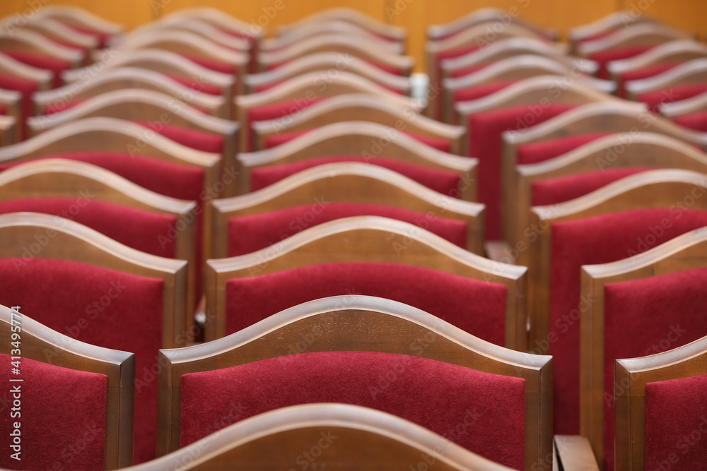 Obraz premium Many red plush chairs with wooden edges stand in rows in the room.Close-up.Selective Focus