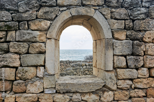 window opening in the ruins of an antique wall  behind which you can see the sea