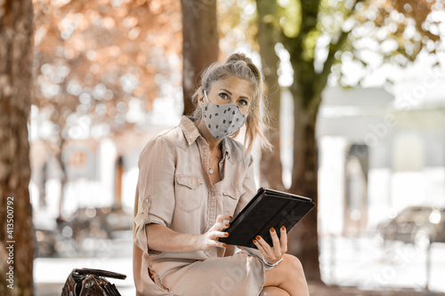 Фотография Woman doing a break outdoors  during the shutdown, reading  on her digital table