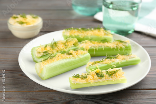 Celery sticks with sauce, cheese and dill on wooden table