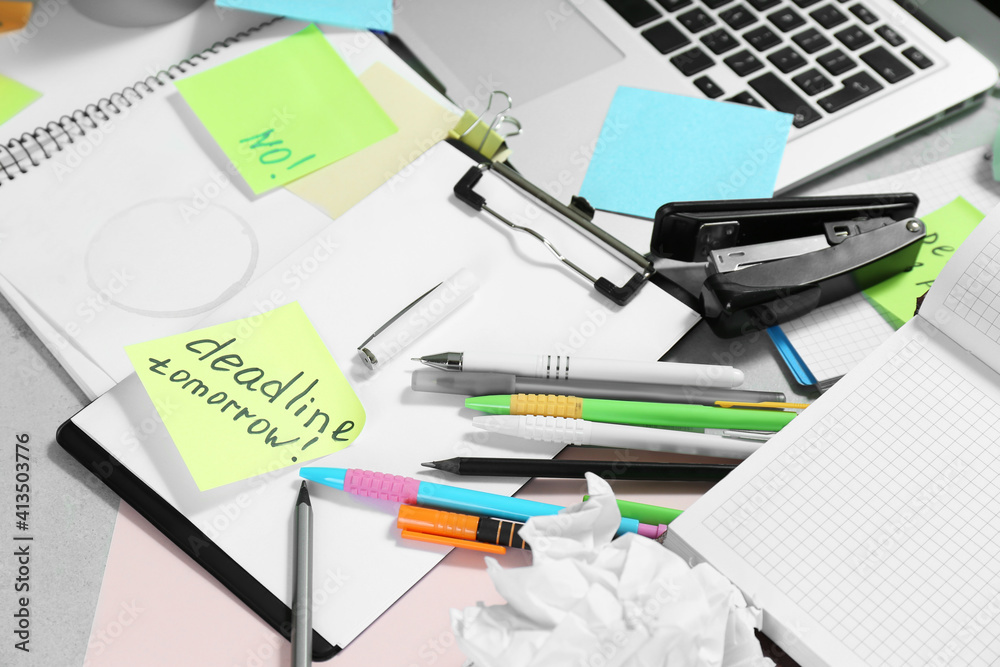 Messy table with laptop and stationery. Concept of being overwhelmed by work Messy table with laptop and stationery. Concept of being overwhelmed by work
