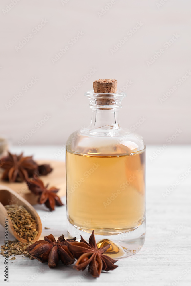 Bottle of essential oil, anise and seeds on white wooden table Bottle of essential oil, anise and seeds on white wooden table
