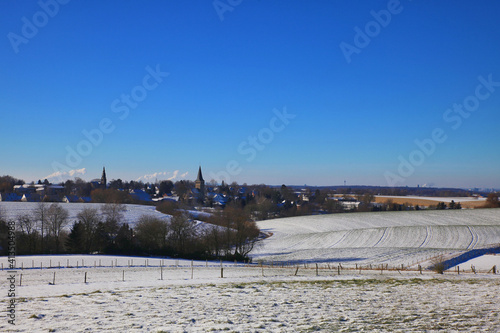 the catholic and protestant church of homberg in winter with snow and blue sky and sun	