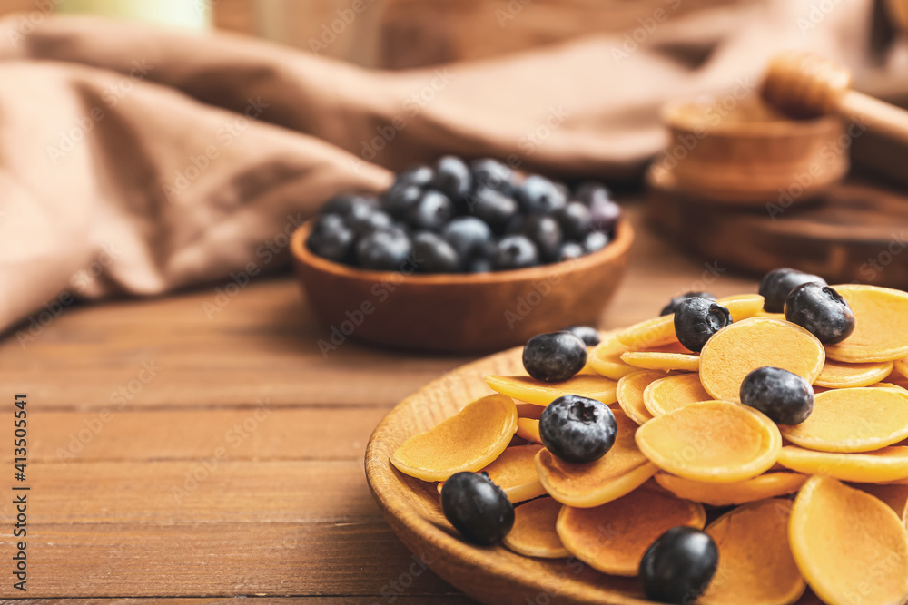Plates of tasty pancakes with fresh blueberry on wooden background, closeup
