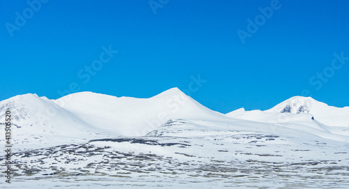 Snow capped mountain peaks against blue sky. © Jon Anders Wiken