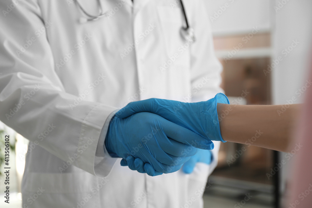 Doctor and patient in protective gloves shaking hands indoors, closeup Doctor and patient in protective gloves shaking hands indoors, closeup