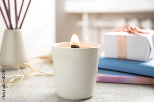 Burning candle with wooden wick on grey table