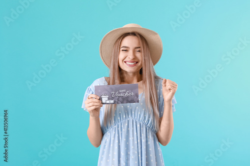 Beautiful young woman with gift voucher on color background photo