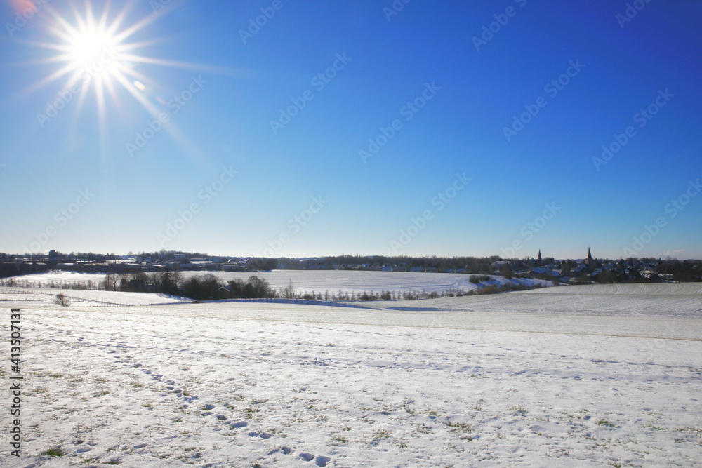the catholic and protestant church of homberg in winter with snow and blue sky and sun	