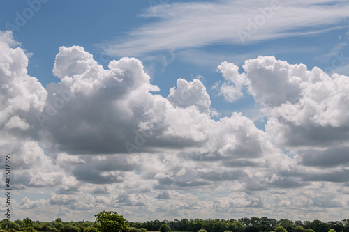 Clouds on a blue sky background with agreen tree border