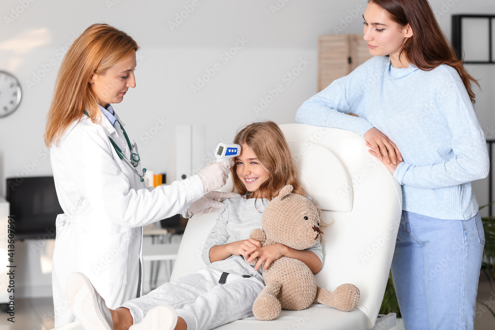 Pediatrician measuring temperature of little girl in clinic Pediatrician measuring temperature of little girl in clinic