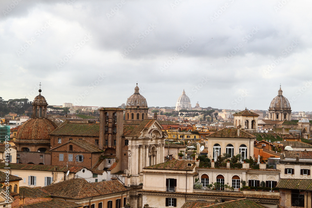 Panorama over the roofs, churches and monuments of Rome, cloudy sky.