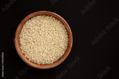 White sesame seeds in a bowl, isolated on black background. photo
