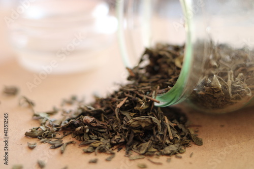 Loose green tea scattered from a glass jar
