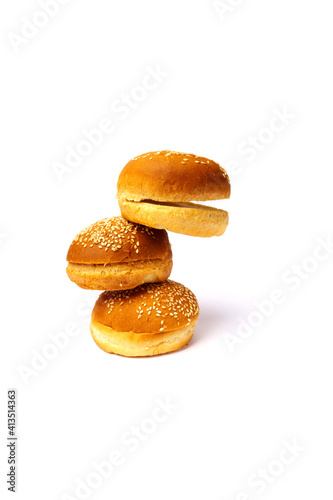 Three hamburger buns with sesame seeds isolated on white background.