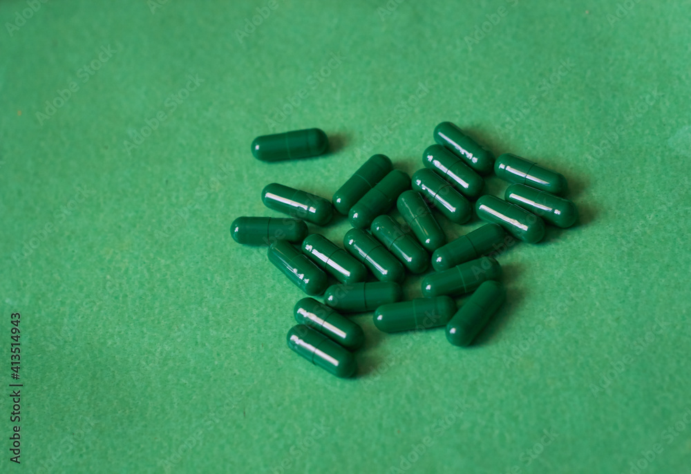 Green capsules on green background. The concept of modern treatment, pharmacy, healthcare. 
