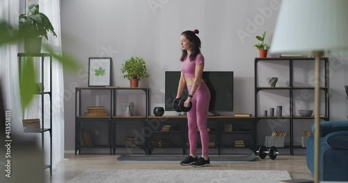 slenderness and good physical condition, training at home for body shaping, slender lady is doing exercises with dumbbell