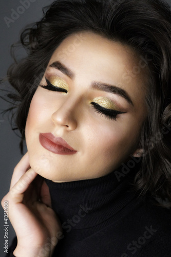 Beautiful young brunette model with bright make-up and curly hair