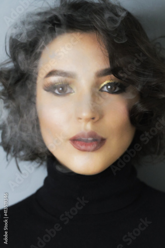Beautiful young brunette model with bright make-up and curly hair